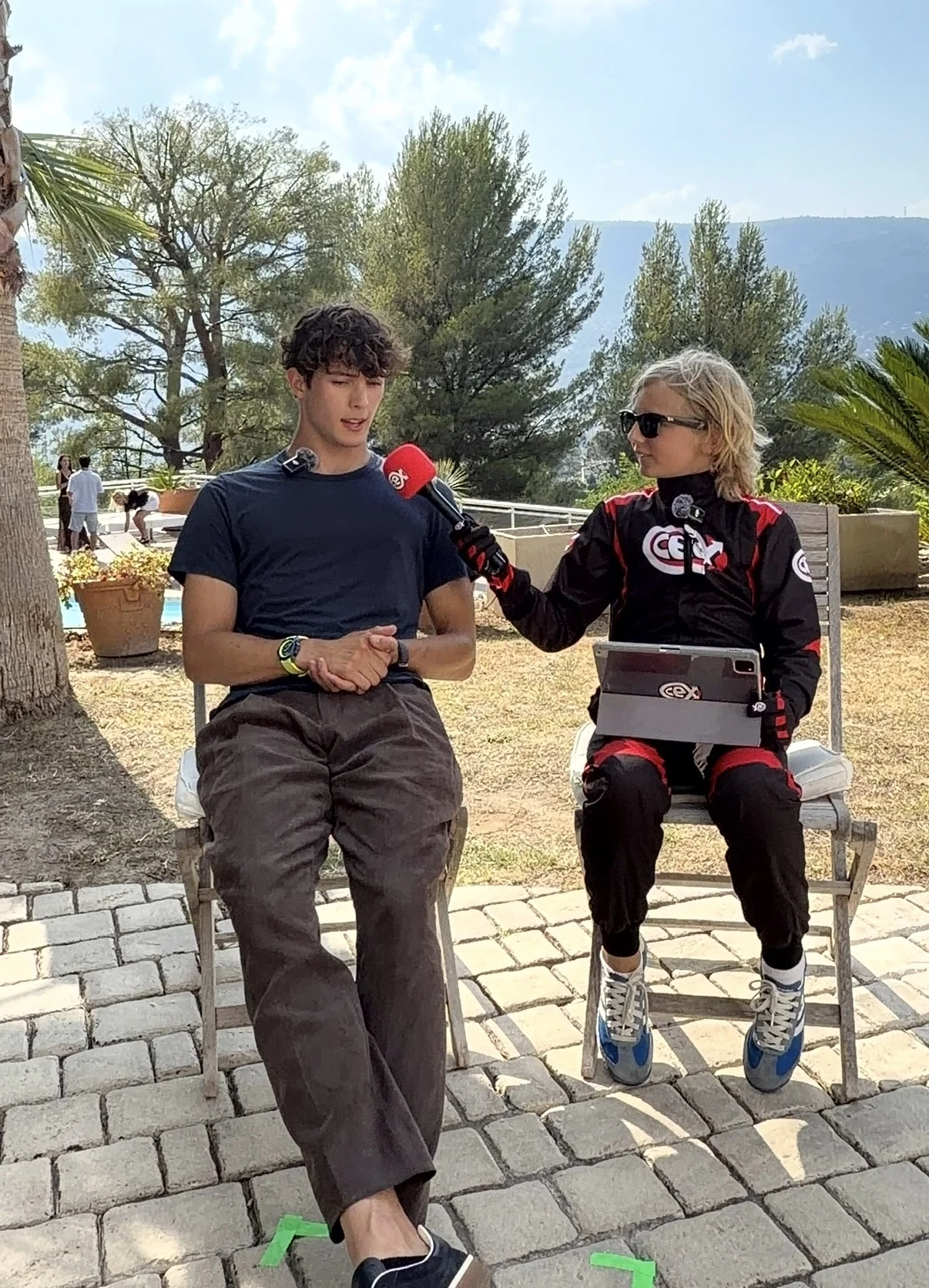 Rocco J Isted holding a CeX microphone while interviewing Ollie Bearman