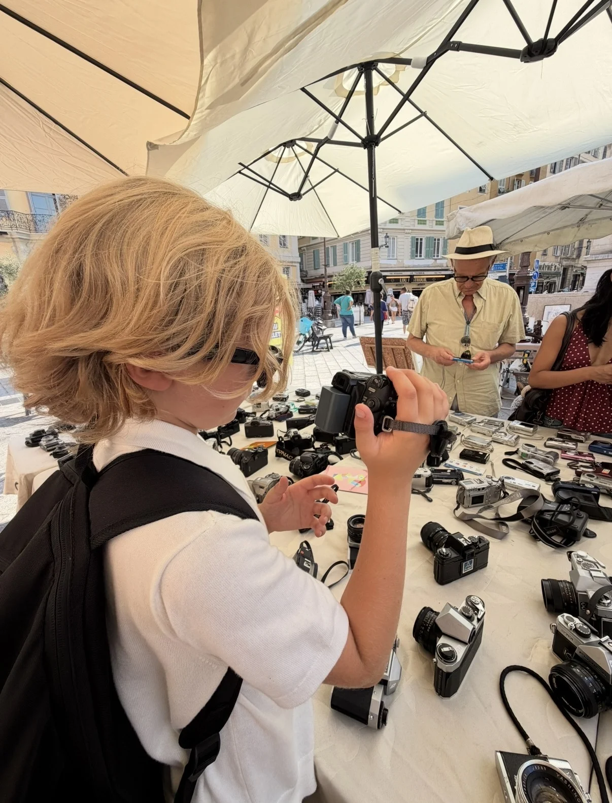 Rocco exploring a collection of cameras at an outdoor market